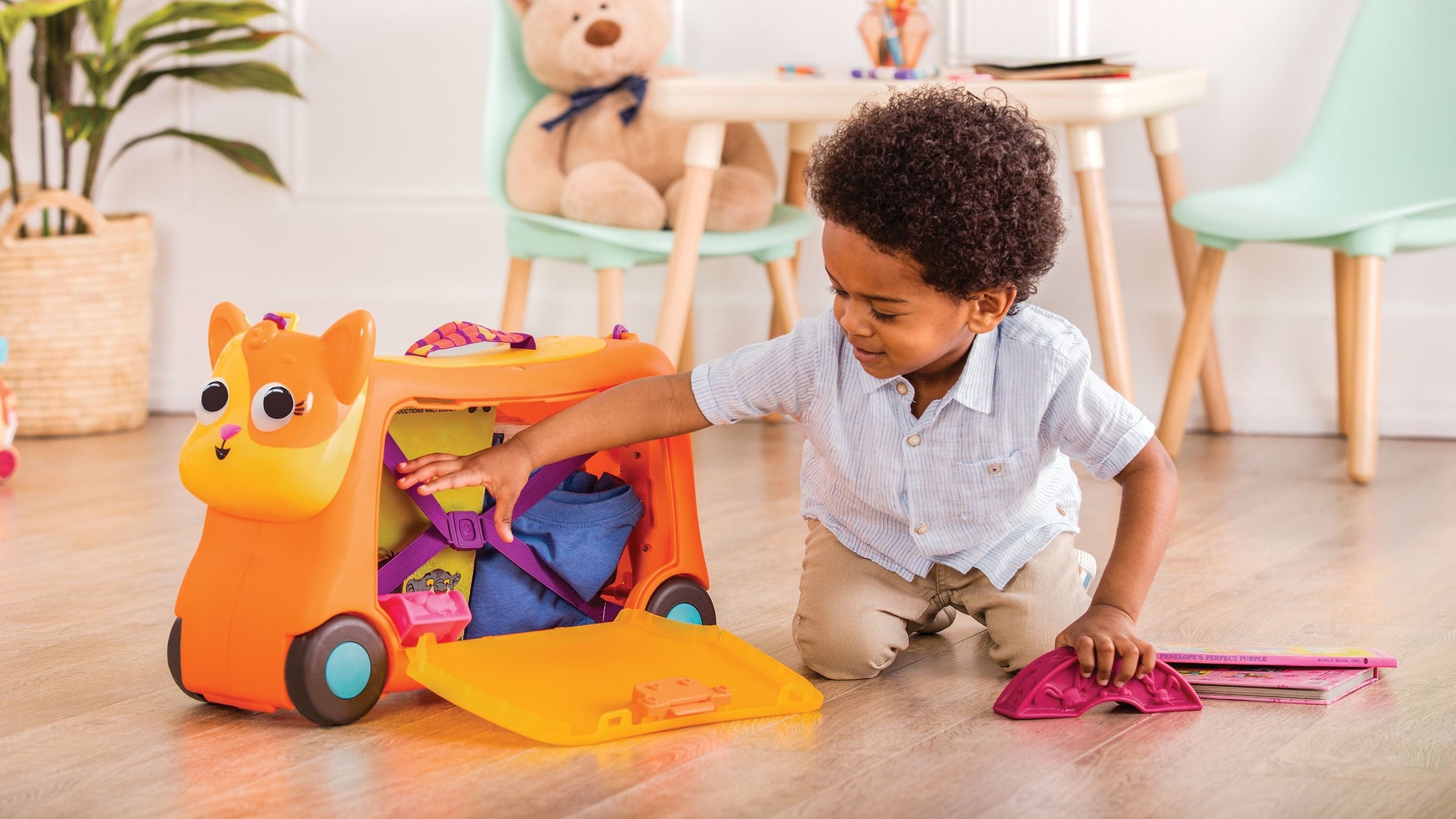 Kid playing with an orange ride on toy with storage space